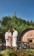 Zwei Gäste im Bademantel im Gartenbereich vor der Sauna des EurothermenResort Bad Schallerbach Hotel Paradiso